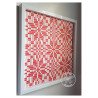 Red and white woven paper snowflake design in white hanging frame by rolling blossoms angled view